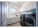 Laundry room equipped with modern black washer and dryer, plus white cabinets at 138 Reflection Cove Dr, Henderson, NV 89011