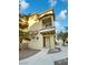 Tan three-story townhouse with balcony and landscaped walkway at 5965 Palmilla St # 2, North Las Vegas, NV 89031