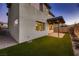 Green turf backyard with covered patio, gravel perimeter, and hose hookup on exterior wall at 6289 Redstone Hills Dr, Las Vegas, NV 89148
