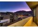 Balcony view overlooking city street with mountain view at sunset, with modern tan-colored home at 6289 Redstone Hills Dr, Las Vegas, NV 89148