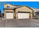 Tan two-story house with a three car garage and brick paver driveway at 1610 Dire Wolf Avenue, North Las Vegas, NV 89084