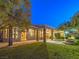 Scenic backyard with a well-maintained lawn, mature trees, a covered patio, and a serene mountain backdrop at dusk at 3 Pine Hollow Dr, Henderson, NV 89052