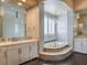 Lavish bathroom with soaking tub, white cabinets, and sinks and glass block shower at 3 Pine Hollow Dr, Henderson, NV 89052