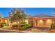 Beautiful single story home at dusk featuring brick veneer, mature landscaping, and three car garage at 3 Pine Hollow Dr, Henderson, NV 89052