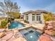 Back exterior view showcasing the pool, spa, covered patio, and surrounding landscape in a well-maintained backyard at 3 Pine Hollow Dr, Henderson, NV 89052