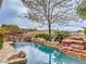 Luxury pool with rock waterfall and surrounding greenery, creating a private and serene outdoor space at 3 Pine Hollow Dr, Henderson, NV 89052