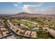 Aerial view showcasing a golf course, lake, and residential area at sunset at 3514 Old Course St, Las Vegas, NV 89122