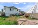 Backyard with a white home, greenhouse, and some untamed greenery at 6324 Fairwood Ave, Las Vegas, NV 89107