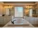 Elegant bathroom with double sinks, soaking tub, and large windows at 10744 Balsam Creek Ave, Las Vegas, NV 89144