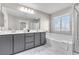 Bright bathroom featuring double sink vanity, framed mirror and soaking tub with a glass shower door at 12815 Alcores St, Las Vegas, NV 89141