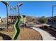 Community playground featuring a slide and climbing structure with surrounding pathways and greenery at 12815 Alcores St, Las Vegas, NV 89141