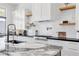 Modern kitchen with marble countertops, black cabinets, and a farmhouse sink at 311 Belfast St, Henderson, NV 89015