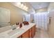 Bright bathroom features a large mirror over a vanity with a white countertop and a tub with a floral shower curtain at 6733 Violet Bluff Ct, North Las Vegas, NV 89084