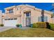 Two-story house with beige exterior, white garage door, and landscaped lawn at 8986 Lillyhammer Ct, Las Vegas, NV 89147