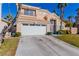 Two-story house with beige exterior, white garage door, and landscaped lawn at 8986 Lillyhammer Ct, Las Vegas, NV 89147