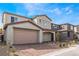 View of the two-story home featuring a brick driveway, neutral color scheme, and desert landscaping at 9247 Lunar Phase St, Las Vegas, NV 89143