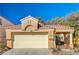 Tan house with a terracotta tile roof, double garage, and gated courtyard at 1809 Derbyshire Dr, Las Vegas, NV 89117