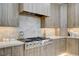 Close-up of a range top in a kitchen with custom cabinets, marble countertop and backsplash, and stainless hood at 3104 Conners Dr, Las Vegas, NV 89107