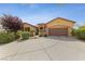 Tan house with a three-car garage and mature landscaping at 10372 Hawks Wing St, Las Vegas, NV 89178