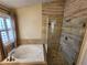 Bathroom with soaking tub and walk-in shower, featuring stone tile at 121 E Cypress Dr, Henderson, NV 89015