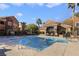 Community pool with clear blue water, seating area, and mature palm trees at 3975 N Hualapai Way # 293, Las Vegas, NV 89129