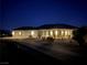 Night view of a single-story home with a three-car garage and well-lit landscaping at 4351 W Bell Vista Ave, Pahrump, NV 89060