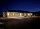 Night view of a single-story home with a three-car garage and landscaped yard at 4351 W Bell Vista Ave, Pahrump, NV 89060