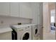 Well-lit laundry room with modern, front-loading washer and dryer and ample cabinet space for storage at 4532 Laguna Vista St, Las Vegas, NV 89147