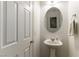 Small bathroom with pedestal sink and round mirror at 5824 Petrified Tree Ln, North Las Vegas, NV 89081