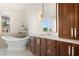 Bright bathroom featuring soaking tub, white marble countertops and dark wood cabinetry at 1635 Liege Dr, Henderson, NV 89012