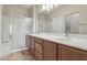 Bright bathroom with double sinks, wood cabinets, and a glass-enclosed shower at 3363 Blue Ribbon Downs St, Las Vegas, NV 89122