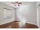 This bedroom features hardwood floors, base trim, a ceiling fan and a large window at 3363 Blue Ribbon Downs St, Las Vegas, NV 89122