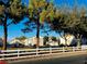 A street view with townhomes visible behind a white fence with mature shade trees and manicured landscaping at 6449 Stone Dry Ave # 101, Henderson, NV 89011