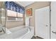 Bathroom with a white soaking tub, white walls, and a window with blue patterned valance at 6914 Willowcroft St, Las Vegas, NV 89149