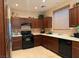 Kitchen with dark brown cabinets, black appliances, and tile floor at 8157 Amy Springs St, Las Vegas, NV 89113