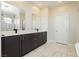 Modern bathroom with dark vanity, double sinks, and marble-look tile flooring at 8224 Skye Territory St, Las Vegas, NV 89166