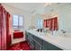 Modern bathroom with double vanity, large mirror and red accents at 9045 Knots Estate St, Las Vegas, NV 89139