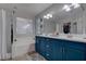 Bathroom with blue vanity, double sinks, and a bathtub at 1112 Via Monticano, Henderson, NV 89052