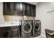 Bright laundry room, featuring dark cabinetry, washer, dryer, and sink at 1557 Mistywood Ct, Henderson, NV 89014