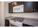 Close-up of stainless steel range and microwave with granite countertops and dark cabinets at 5391 Kennedy Hill Ave, Las Vegas, NV 89139