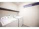 Well-lit laundry room with white washer and dryer set and dark wood shelf at 5391 Kennedy Hill Ave, Las Vegas, NV 89139