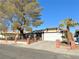 Single-story house with a white garage door, mature tree, and brick fence at 6402 Agua Dr, Las Vegas, NV 89103