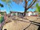 House exterior with a large tree, brick fence, and gravel yard at 6402 Agua Dr, Las Vegas, NV 89103