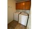 Bright laundry room with washer, dryer, and wood cabinets at 938 Cantabria Heights Ave, Las Vegas, NV 89183