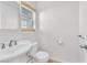 Bright half-bathroom with a pedestal sink, white toilet, and a window for natural light at 10452 Prairie Schooner Ave, Las Vegas, NV 89129