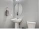 Simple bathroom with pedestal sink, toilet, and oval mirror at 6201 Ashley Hills Ave, Las Vegas, NV 89141