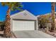 Front view of a house with a white garage door and palm trees at 9612 World Cup Dr, Las Vegas, NV 89117