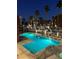 Beautifully lit outdoor swimming pool with palm trees and apartment buildings at nighttime at 23 E Agate Ave # 506, Las Vegas, NV 89123
