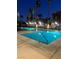 Outdoor pool and lounge area with palm trees and nearby condos in the background at nighttime at 23 E Agate Ave # 506, Las Vegas, NV 89123