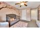 Cozy bedroom with crib, ceiling fan and pink tree wall art at 10166 Bishops Peak Ct, Las Vegas, NV 89141